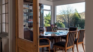 A dining area with a table, chairs, and a view of trees outside.