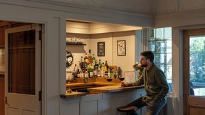 A bar area with a counter, shelves with bottles, and a window with a view.
