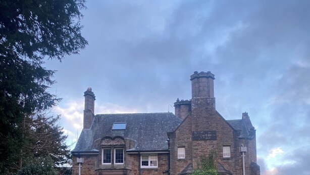 A stone building with a traditional design, a paved pathway, and a well-maintained lawn.