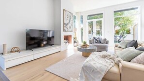 Ett modernt vardagsrum med en platt-TV, en soffa, ett soffbord och en öppen spis.
