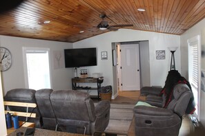 A living room with leather recliners, a flat-screen TV, and a ceiling fan.