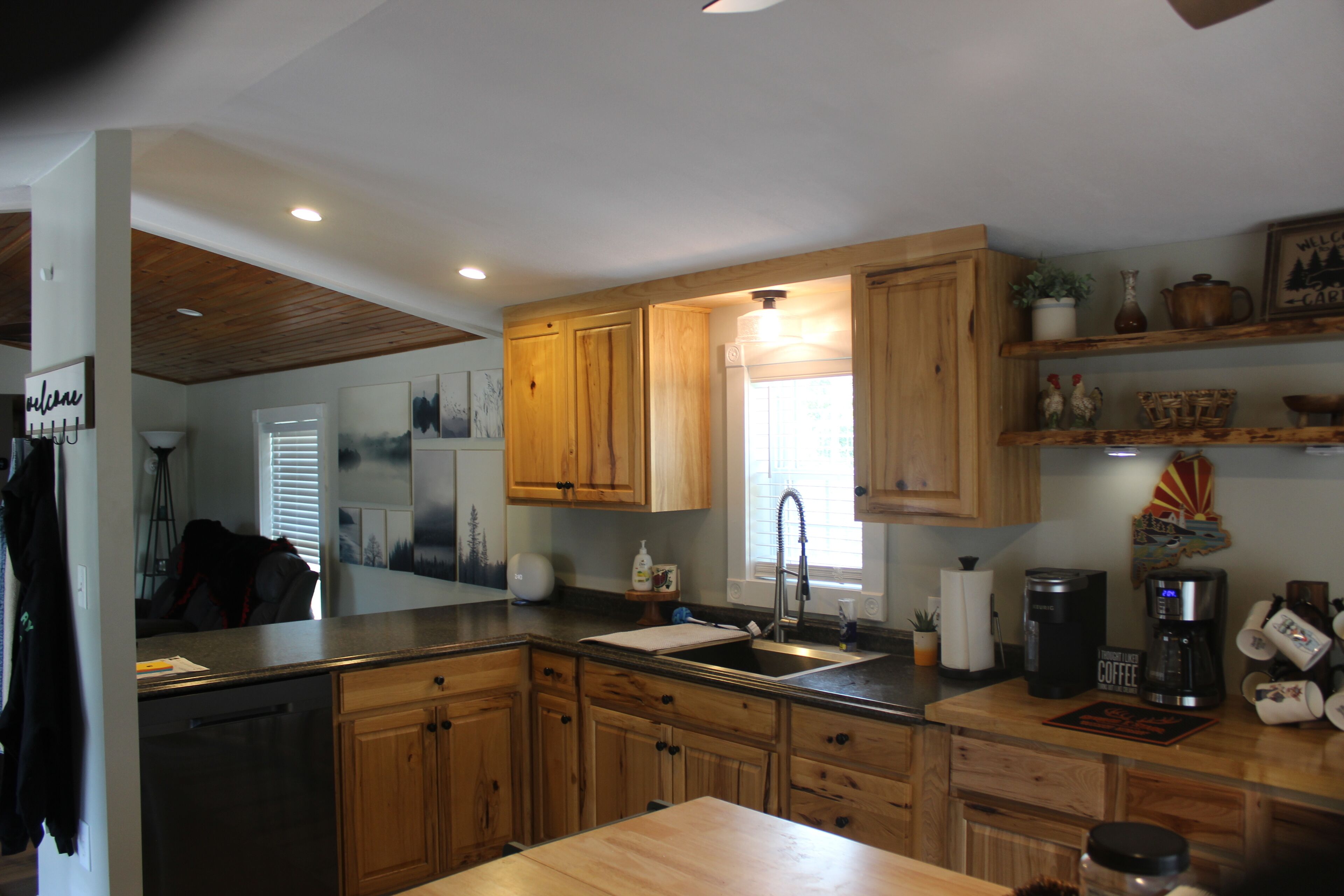 A kitchen with wooden cabinets, a sink, a coffee maker, and a window with blinds.