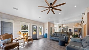 A spacious living room with a ceiling fan, a dining area with wooden chairs, and a kitchen in the background. - Resort Feel Home, Private Pool,spa,hammocks. Beach,owa,wharf-15min, 5 Bedrooms (Foley)