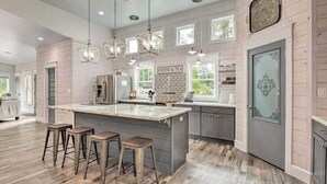 A modern kitchen with a central island, bar stools, pendant lighting, and a 'Coffee & Tea' sign. - Resort Feel Home, Private Pool,spa,hammocks. Beach,owa,wharf-15min, 5 Bedrooms (Foley)