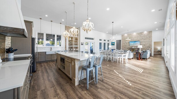 A spacious kitchen with a large island, modern pendant lights, and a dining area with chairs and a table. - Large Lux Home,private Pool,spa,backyard, 6 Bdrms, Beach,wharf, OWA 15 Mins Away (Foley)