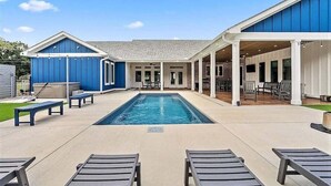 A pool area with lounge chairs, a covered patio, and a blue building. - Large Lux Home,private Pool,spa,backyard, 6 Bdrms, Beach,wharf, OWA 15 Mins Away (Foley)