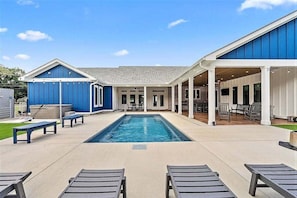A pool area with lounge chairs, a covered patio, and a blue building. - Large Lux Home,private Pool,spa,backyard, 6 Bdrms, Beach,wharf, OWA 15 Mins Away (Foley)