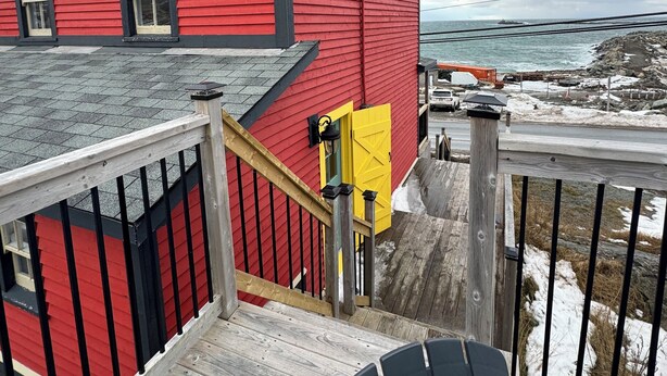 A red building with a wooden deck and a yellow door. - The Historical William Ellis Saint House (Bonavista)