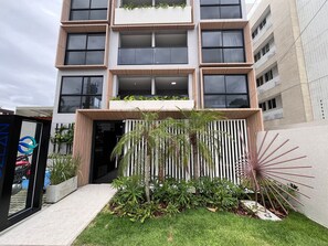 En bygning med flere etager i moderne stil, med store vinduer og en central indgang prydet med plantearrangement.