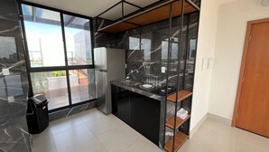 A modern kitchen with a black marble backsplash, stainless steel appliances, and a glass-enclosed window. - Flat Comfort La Belle Formosa - Cabedelo (Cabedelo)