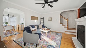 A spacious living room with a gray sofa, a coffee table, and a fireplace. There is a staircase leading to another level. - Appealing 2br Cape Cod w/ bonus rm & fiber Wi-Fi! (Toledo)
