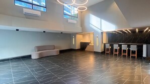 Un'ampia hall con un'area salotto a forma di curva, una reception e un angolo bar con sgabelli.