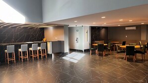 Una hall d'albergo moderna con area bar, posti a sedere e un'ampia finestra che offre luce naturale.