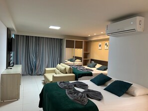A hotel room with two beds, a desk, a chair, a wardrobe, and an air conditioning unit. - Flat Premium Sea View - Tabatinga Beach (Conde)