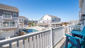 Ett bostadsområde med flera hus, en swimmingpool och en balkong med en stol.