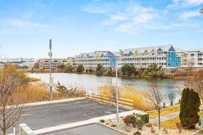 A waterfront hotel with colorful buildings, a parking lot, and a lake. - Broad Marsh Breeze | Pool, Kayak & Near Beach (Ocean City)