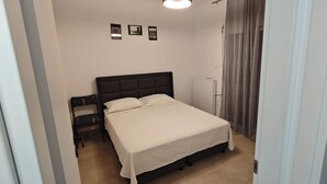 A bedroom with a bed, a nightstand, a radiator, and three framed pictures on the wall.