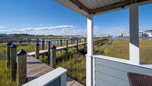 Une terrasse en bois couverte, offrant une vue sur un port de plaisance et les bâtiments situés de l’autre côté de l’eau.
