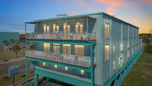 Un bâtiment à deux étages, doté de balcons et de nombreuses fenêtres, situé dans un espace verdoyant sous un ciel dégagé.