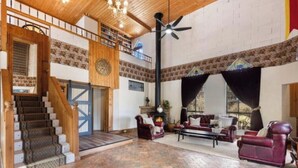 A spacious living area with a fireplace, comfortable seating, and a staircase leading to an upper level. - The Castle: Off-Grid Retreat nestled in the Sedgwick Valley 20 mins from Bendigo (Sedgwick)