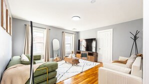 Een moderne woonkamer met een bank, een salontafel, een televisie en een spiegel.