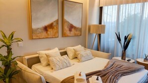 A hotel room with a bed, pillows, a bedside table, a lamp, a plant, and artwork on the wall. - Luxury UCAM Studio | Desk & High-Speed Wi-Fi (Guadalupe)