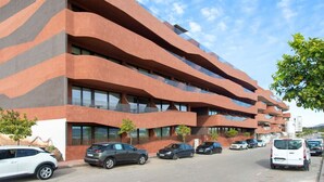 Un immeuble à plusieurs étages doté d’une architecture moderne, avec des balcons et de grandes fenêtres.