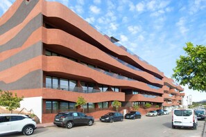Un edificio de varios pisos con un diseño arquitectónico moderno, con balcones y grandes ventanales.