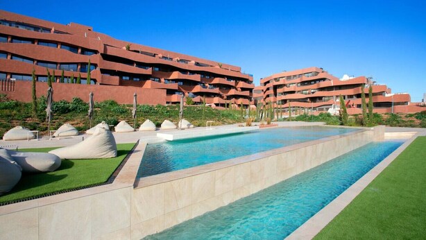 A swimming pool with a clear blue water, surrounded by green grass and white spherical seating. - Luxury UCAM Studio | Desk & High-Speed Wi-Fi (Guadalupe)
