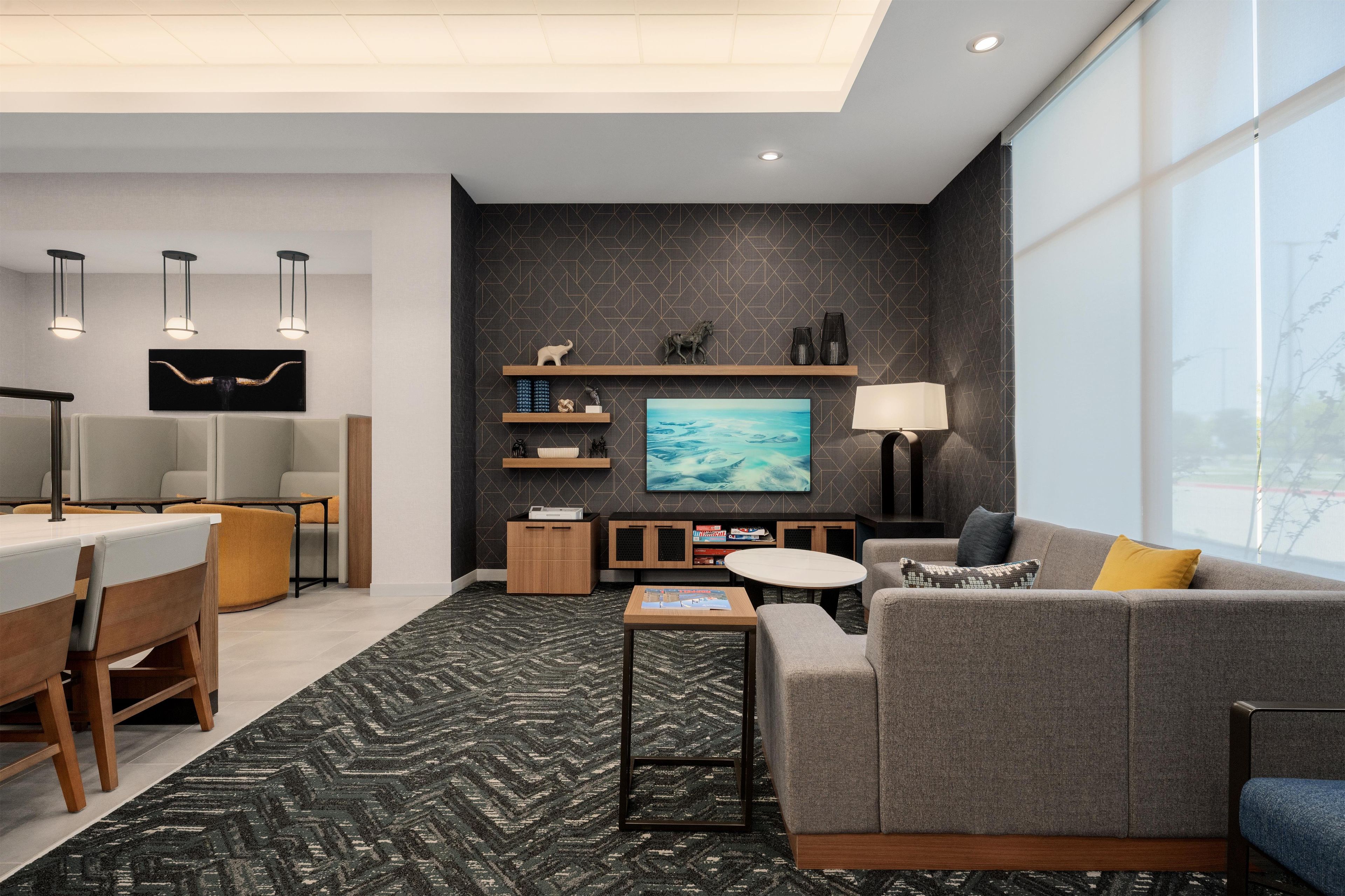 A modern living room with a grey sofa, a coffee table, a TV, and a fireplace.