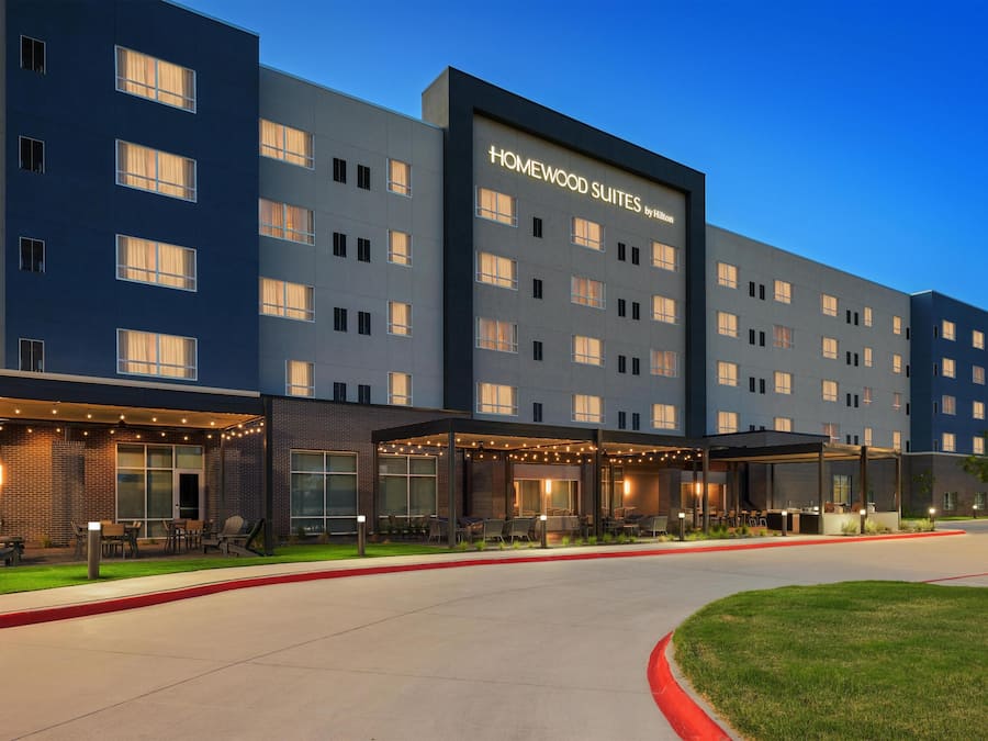 Un hotel moderno con varios pisos, zonas de estar al aire libre y cielo despejado.