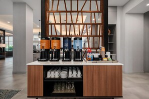 A coffee station with four dispensers labeled 'Regular Coffee,' 'Decaf Coffee,' and 'Hot Water,' and a coffee maker. - Homewood Suites By Hilton Coppell Dfw Airport North (Coppell)