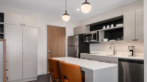A modern kitchen with a central island, stainless steel appliances, and a built-in oven. - Homewood Suites By Hilton Coppell Dfw Airport North (Coppell)