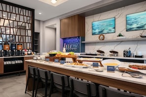 A modern kitchen with a marble countertop, bar seating, and a coffee station.