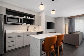 A modern kitchen with a central island, built-in appliances, and a dining area with a sofa and chairs.