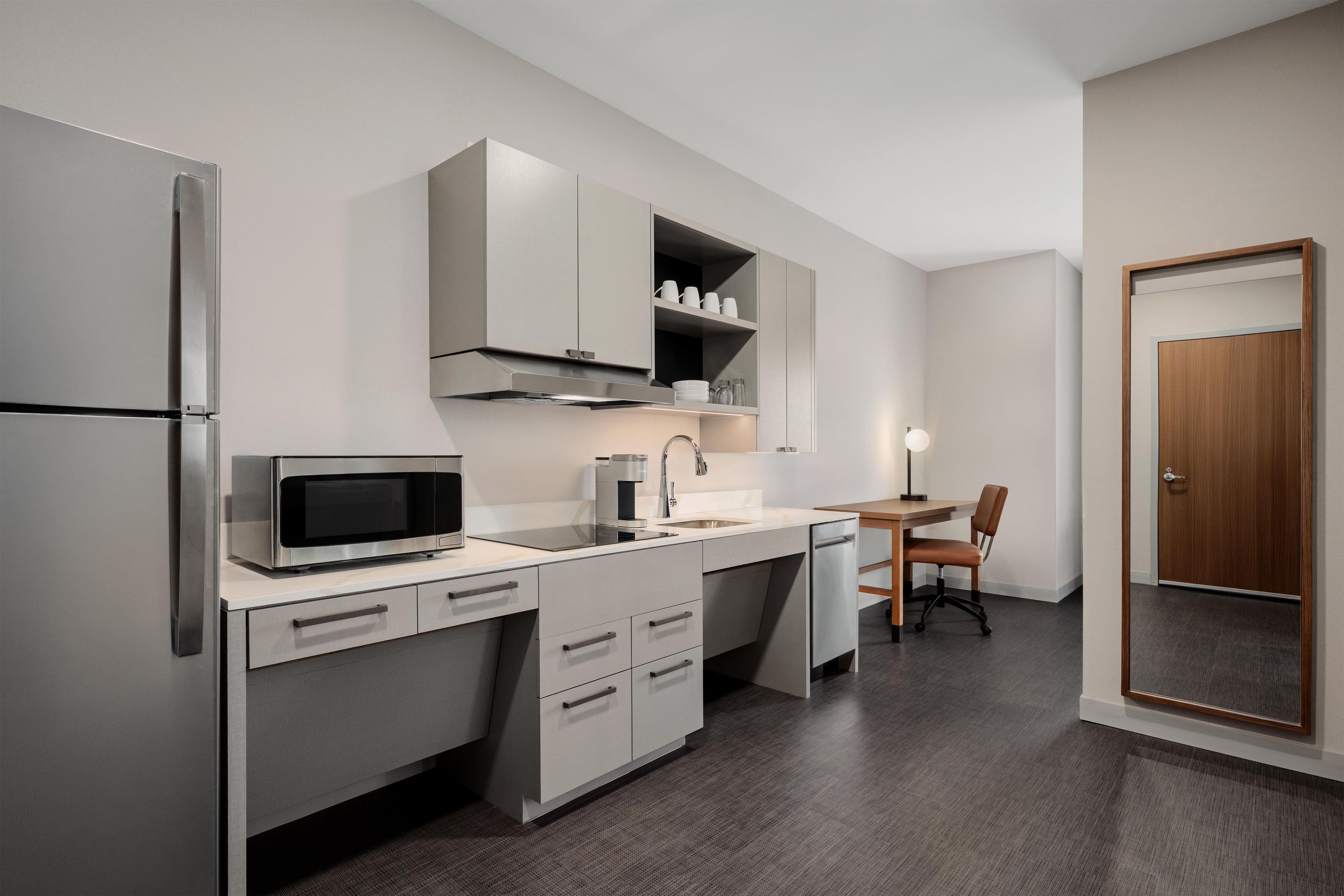 A compact kitchen with a microwave, coffee maker, and a small dining area with a table and chair.