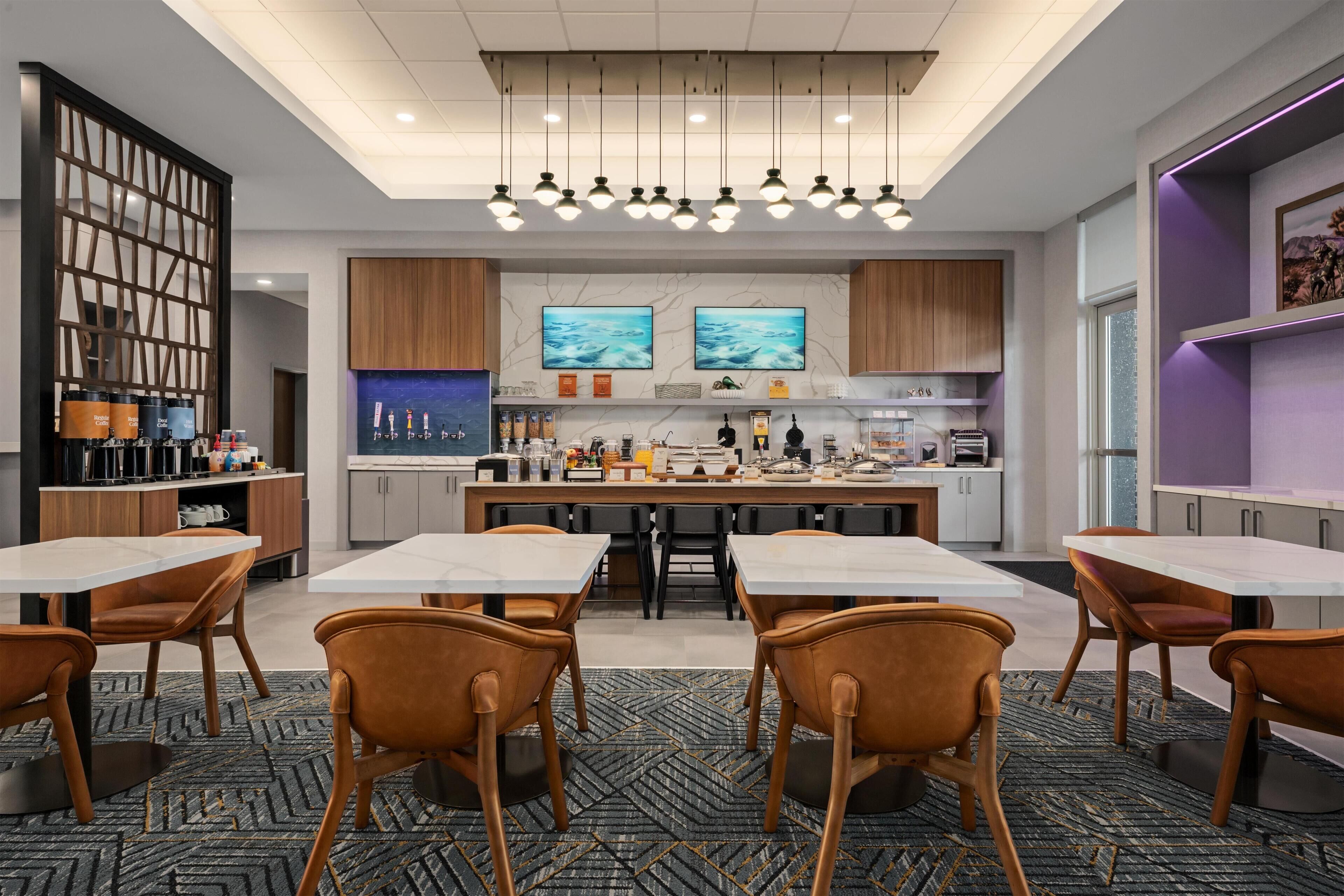 A modern kitchen with a central island, bar seating, and a dining area with chairs.