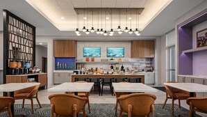 A modern kitchen with a central island, bar seating, and a dining area with chairs. - Homewood Suites By Hilton Coppell Dfw Airport North (Coppell)
