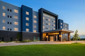 Un hôtel moderne, avec un bâtiment à la façade plate, de nombreuses fenêtres et un espace d’entrée abrité.