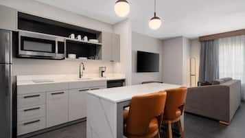 A modern kitchen with a central island, built-in appliances, and a dining area with a sofa and chairs.