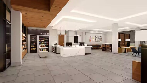 A modern hotel lobby with a reception desk, a 'Suite Shop' with shelves of toiletries, and a seating area with tables and chairs. - Homewood Suites By Hilton Coppell Dfw Airport North (Coppell)
