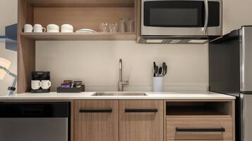 A modern kitchen with a built-in microwave, coffee maker, and a stainless steel refrigerator.