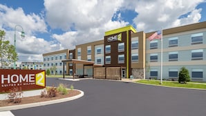 Un hôtel avec une enseigne indiquant « HOME 2 SUITES BY HILTON » et un drapeau américain.