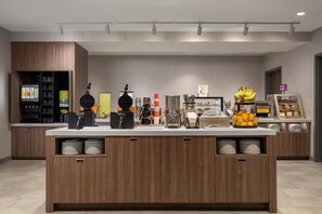 Una barra de desayuno moderna con máquina de café, plancha para gofres y exhibición de frutas.
