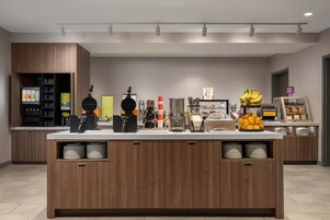 Una barra de desayuno moderna con máquina de café, plancha para gofres y exhibición de frutas.