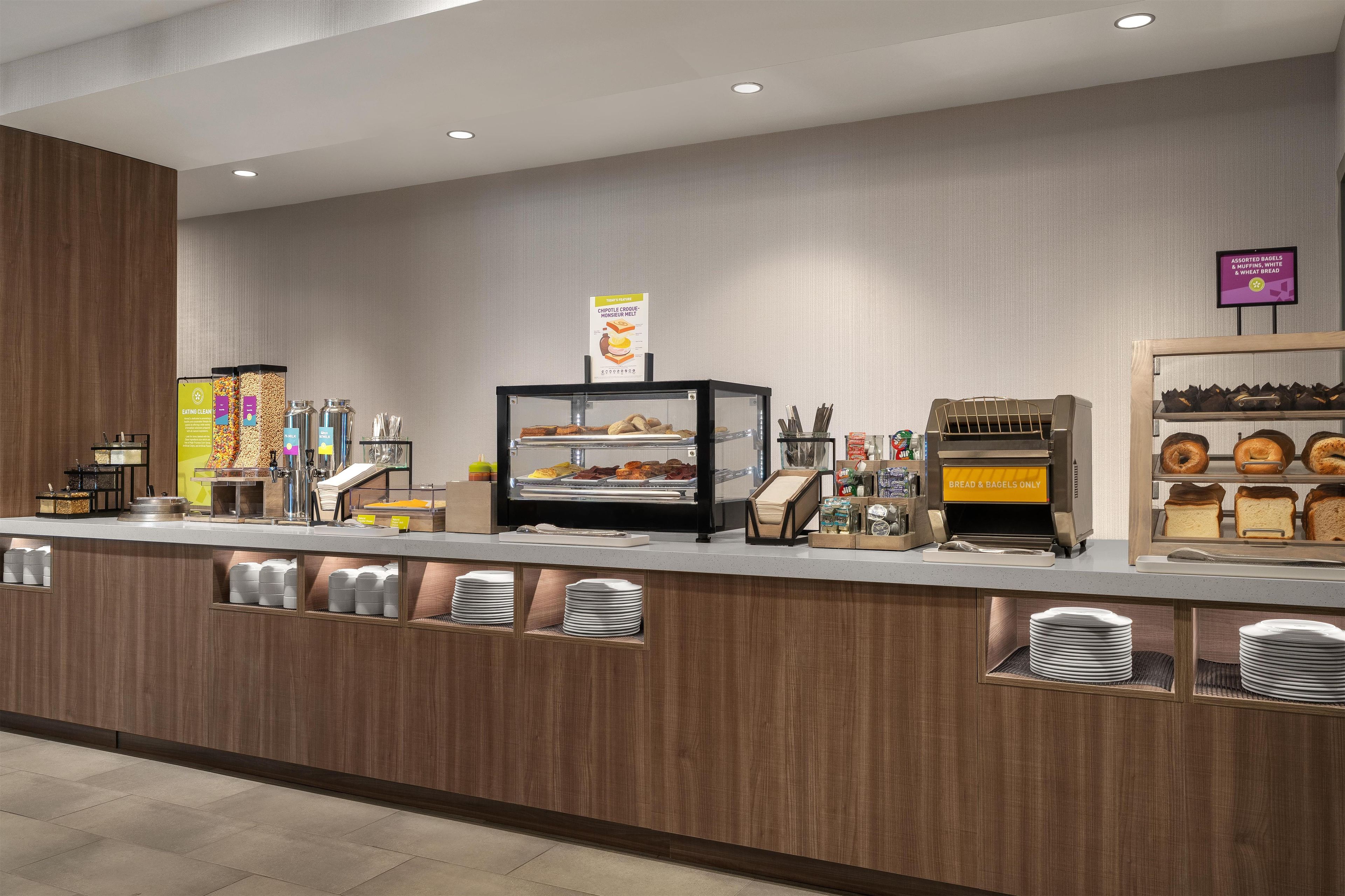 A self-service breakfast station with a variety of food options, including cereals, bread, and pastries.