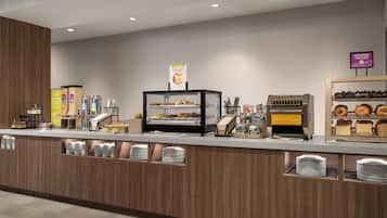 A self-service breakfast station with a variety of food options, including cereals, bread, and pastries.