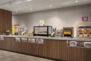 Un buffet pour le petit-déjeuner où chacun se sert, proposant un choix varié d’aliments, notamment des céréales, du pain et des viennoiseries.