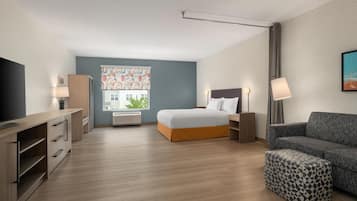 Una habitación de hotel moderna con cama, sofá, televisor y escritorio.