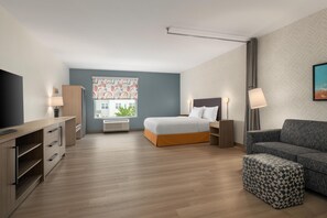 Una habitación de hotel moderna con cama, sofá, televisor y escritorio.